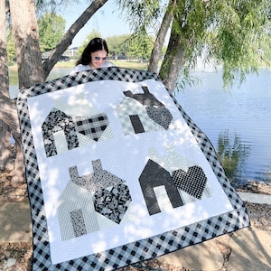 May include: A black and white quilt with a checkered border. The quilt features four houses with hearts in the center of each house. The houses are made of different fabrics with black and white patterns.