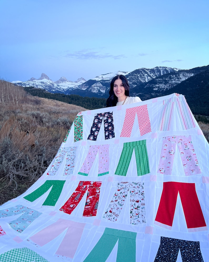 Fam Jam Quilt pattern held by Jen @thesmittenchicken with the snowy Tetons as background