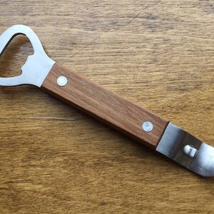 May include: A bottle opener with a stainless steel head and a wooden handle. The opener has a bottle cap opener and a can piercer. The handle is made of brown wood and is attached to the metal head with two silver rivets.