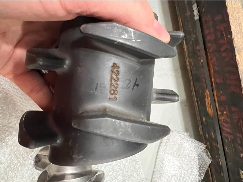 May include: A dark gray metal component with a series of blades and the number "422281" printed on the side. The component has a complex shape with multiple protrusions and a textured surface. The item is held by a hand.