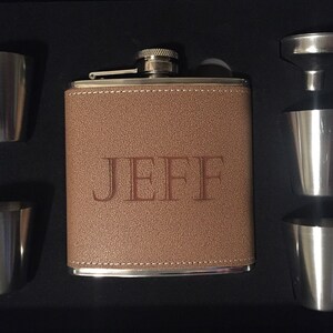 Pu&ograve; includere: Un set di fiaschetta personalizzato in una scatola nera. La fiaschetta marrone rivestita in pelle &egrave; incisa con il nome "JEFF". Il set include quattro bicchierini in acciaio inossidabile e un imbuto. Un'ottima idea regalo.