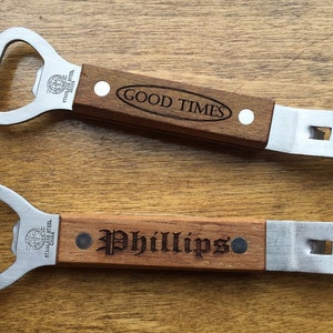 May include: Two bottle openers with wooden handles and stainless steel heads are displayed. One opener has "GOOD TIMES" engraved, the other has "Phillips". Both have a bottle cap opener and a pry-off feature.