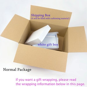 May include: A brown cardboard shipping box with the top open, revealing a white gift box inside. The text "Shipping Box (It will be filled with cushioning material.)" is printed on the box. The text "white gift box" is written on the white box. The text "Normal Package" is printed below the box. The text "If you want a gift wrapping, please read the wrapping information below in this page." is printed below the text "Normal Package."