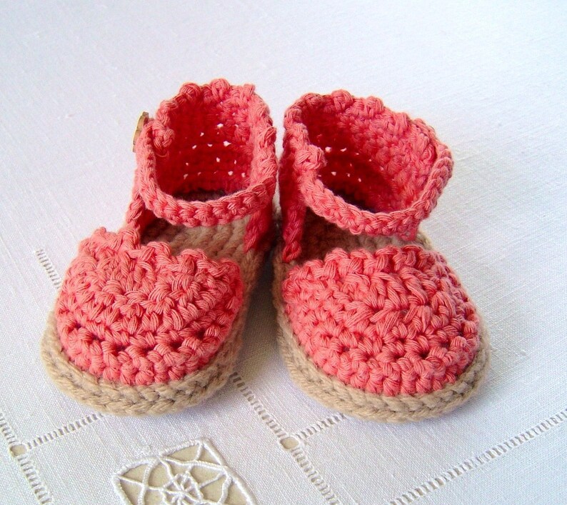 May include: A pair of crocheted baby sandals in a coral pink color with a brown sole.