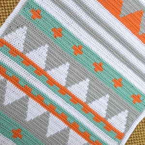 May include: A crocheted blanket with a geometric pattern in shades of gray, white, orange, and teal.