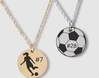 Könnte beinhalten: Zwei silberne Halsketten mit runden Anhängern. Ein Anhänger zeigt eine schwarze Silhouette eines Fußballspielers mit der Nummer "#7" und der andere Anhänger zeigt einen schwarz-weißen Fußball mit der Nummer "#28".