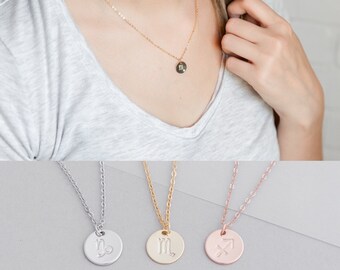May include: Three gold necklaces with zodiac signs. The necklaces are silver, gold, and rose gold. The signs are Sagittarius, Scorpio, and Capricorn.