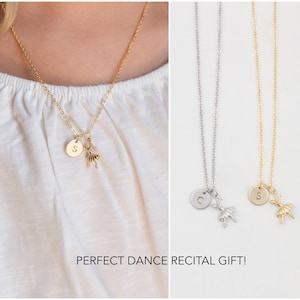 Pu&ograve; includere: Due collane d'oro con un ciondolo a forma di ballerina e un disco iniziale personalizzato. Le collane sono su uno sfondo bianco. Il testo "PERFECT DANCE RECITAL GIFT!" &egrave; scritto sotto le collane.
