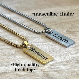 May include: Two pendant necklaces with rectangular tags. One is silver with "Liam" engraved, the other is gold with "Bennett" engraved. The chains are a box style. Text reads "masculine chain" and "High quality, thick tag."