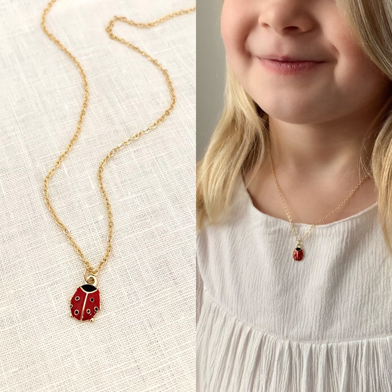 Pu&ograve; includere: Una collana con catena dorata con un piccolo ciondolo a forma di coccinella rossa. La collana &egrave; indossata da una bambina con i capelli biondi.