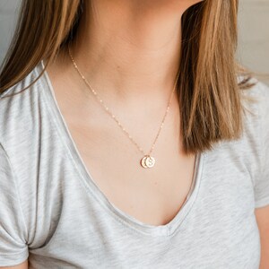 Puede incluir: Un collar de cadena de oro con dos peque&ntilde;os discos de oro colgando de &eacute;l. Los discos tienen las letras "S" y "C" grabadas.