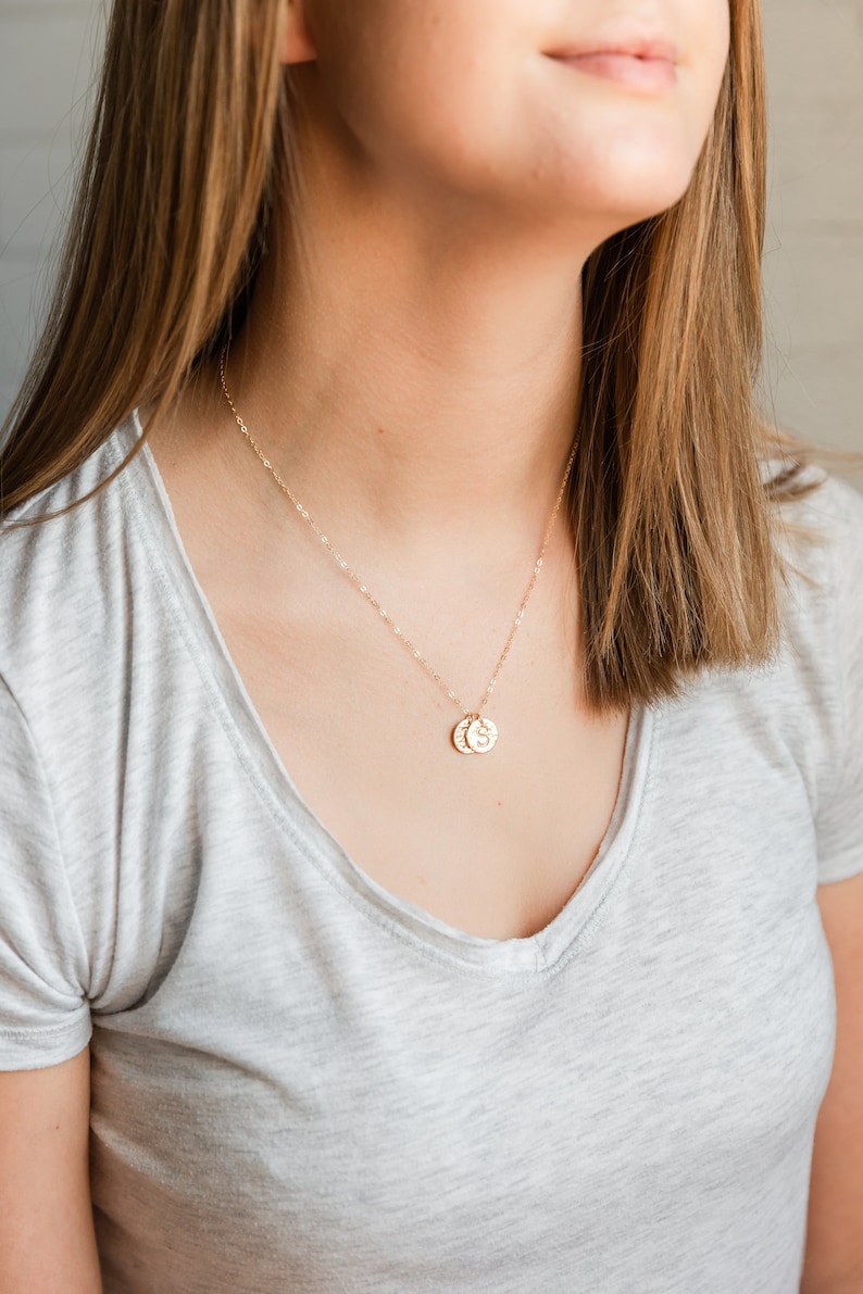 Puede incluir: Un collar de cadena de oro con dos peque&ntilde;os discos de oro colgando de &eacute;l. Los discos tienen las letras "S" y "C" grabadas.