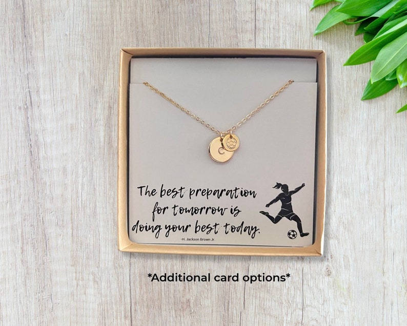May include: A gold necklace with a soccer ball charm and a letter charm in a gift box. The box has a card with the quote "The best preparation for tomorrow is doing your best today." and a silhouette of a soccer player.