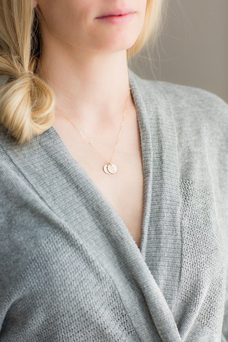 Puede incluir: Un delicado collar de oro con dos peque&ntilde;os colgantes redondos. El collar lo lleva una persona que lleva un su&eacute;ter gris.