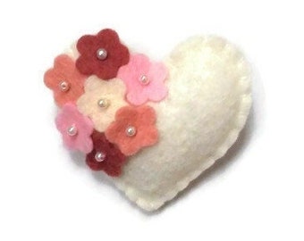 May include: A white felt heart with a cluster of pink, red, and peach felt flowers with pearl centers.