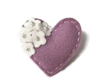 May include: A purple felt heart with white felt flowers and pearl accents.