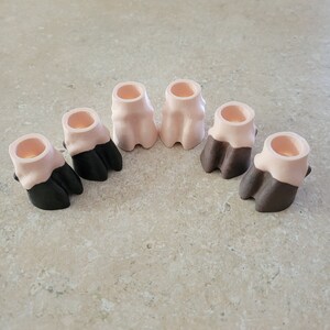 Könnte beinhalten: Sechs kleine Keramik-Tierpfoten, in Pink und Schwarz bemalt. Die Pfoten sind in einem Halbkreis angeordnet.