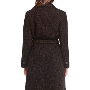 May include: A brown tweed coat with a belt and long sleeves. The coat has a classic design and is perfect for autumn and winter.