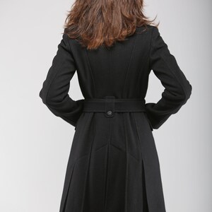 May include: A black wool coat with a belt and a pleated skirt. The coat has a classic design and is perfect for colder weather.