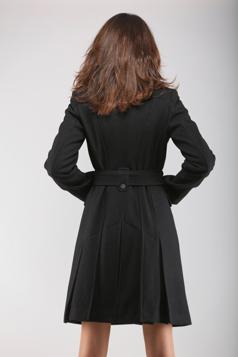 May include: A black wool coat with a belt and a pleated skirt. The coat has a classic design and is perfect for colder weather.