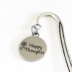 May include: Silver bookmark with a round charm that says "Happy Thoughts" with a small flower design.