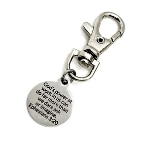 May include: Silver keychain with a round tag that reads "God's power at work in us can do far more than we dare ask or imagine. Ephesians 3:20".