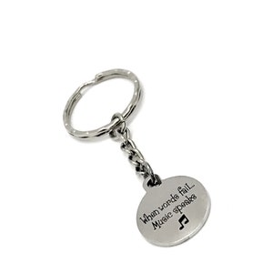 May include: Silver keychain with a round charm that says "When words fail... Music speaks" with a musical note symbol.
