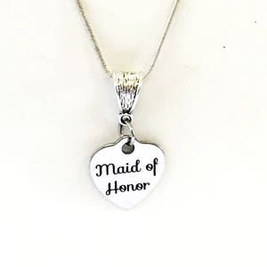 Puede incluir: Collar de plata con un colgante en forma de coraz&oacute;n que dice "Maid of Honor".