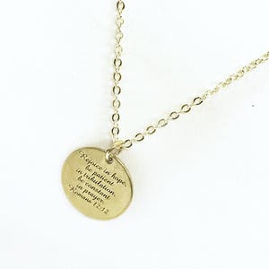 Op de afbeelding: Gouden ketting met een ronde hanger met de tekst "Verheug je in de hoop, wees geduldig in de verdrukking, wees standvastig in het gebed. Romeinen 12:12"