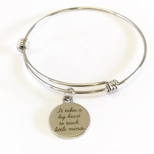 Peut inclure: Un bracelet extensible en argent avec un charme qui dit "Il faut un grand cœur pour enseigner aux petits esprits".
