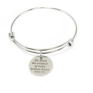 May include: Silver bangle bracelet with a charm that reads "He heals the wounds of every broken heart. Psalm 147:3".