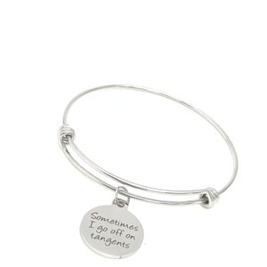 May include: Silver bangle bracelet with a round charm that says "Sometimes I go off on tangents".