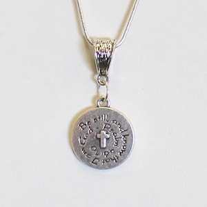 May include: A silver necklace with a round pendant that says "Be still and know that I am God" with a cross in the center.