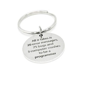 Può includere: Un portachiavi argentato con un ciondolo rotondo che recita "All it takes is 20 error messages, 75 bugs and 3 computer crashes to be a programmer".