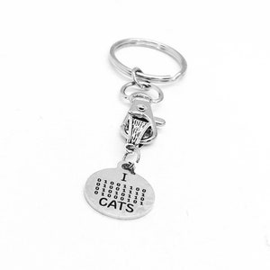 May include: Silver keyring with a round charm that says "I  CATS" in binary code. The charm is attached to a silver split ring and a silver lobster clasp.
