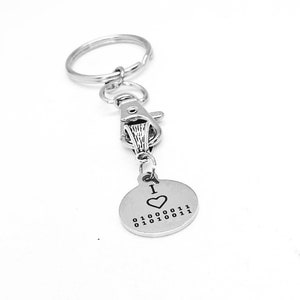 Può includere: Portachiavi d'argento con un ciondolo rotondo che dice "I ♥ 01000011 01000011 01000011".