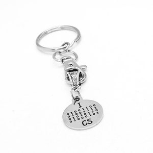 May include: Silver keyring with a round charm that says "I  CS" and has a binary code for the letter "I".