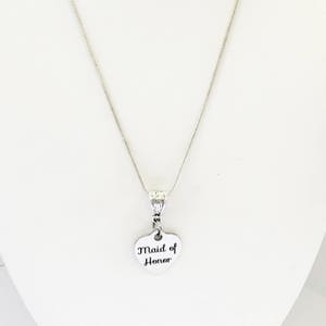 Puede incluir: Collar de plata con un colgante en forma de coraz&oacute;n que dice "Maid of Honor".