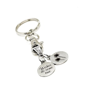 May include: Silver keyring with two round charms. One charm has the text "Wishes do come true" and the other charm has a silhouette of two dandelions.