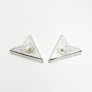 May include: Two silver corner bookmarks with a white center and a gold dot in the center.