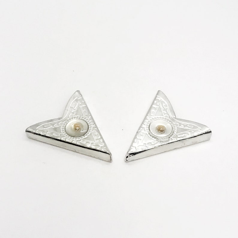 May include: Two silver corner bookmarks with a white center and a gold dot in the center.