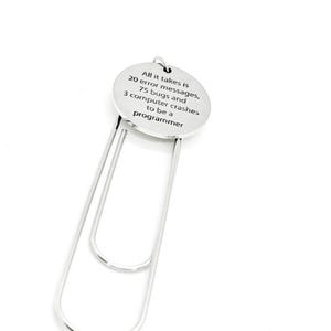 Può includere: Segnalibro d'argento con un ciondolo rotondo che recita "Ci vogliono 20 messaggi di errore, 75 bug e 3 crash del computer per essere un programmatore".