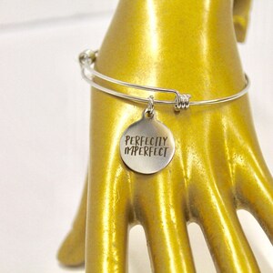 Peut inclure: Bracelet en argent avec un charme qui dit "Parfaitement imparfait".