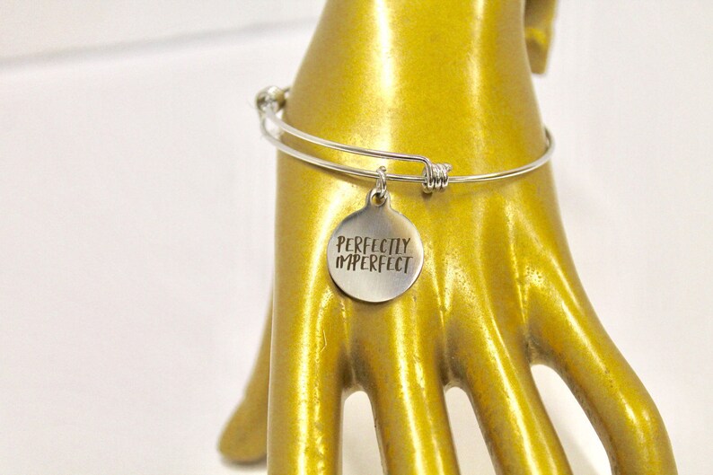 Peut inclure: Bracelet en argent avec un charme qui dit "Parfaitement imparfait".