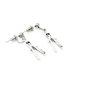 Puede incluir: Un par de pendientes de plata en forma de compás. Los pendientes son de estilo colgante con un poste de plata y un bucle de plata.