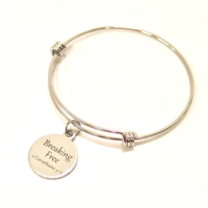 May include: Silver expandable bangle bracelet with a round charm that reads "Breaking Free 2 Corinthians 3:17".