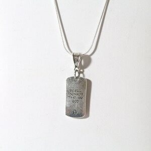 May include: Silver necklace with a silver tag pendant that reads "Be still and know that I am God".