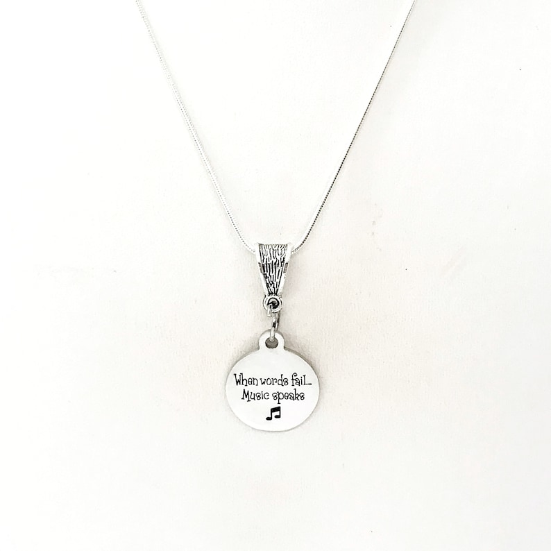 May include: Silver necklace with a round pendant that says "When words fail... Music speaks" with a musical note symbol.