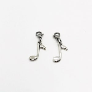 Pode incluir: Dois pingentes de prata em forma de nota musical com um fecho de lagosta de prata. Os pingentes est&atilde;o pendurados nos fechos.