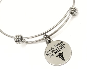 May include: A silver expandable bangle bracelet with a round charm that says "Gastric Sleeve No Blind NG. No NSAIDS" with a medical symbol.